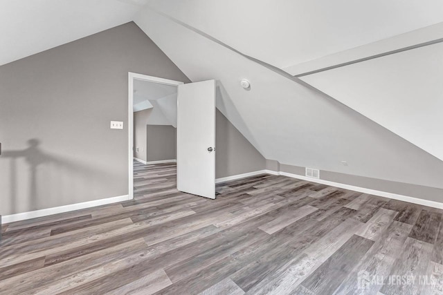 additional living space with hardwood / wood-style floors and lofted ceiling