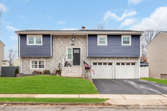 raised ranch featuring a garage and a front lawn