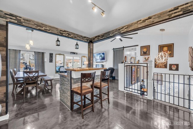 interior space featuring ceiling fan, decorative light fixtures, a kitchen bar, and a barn door