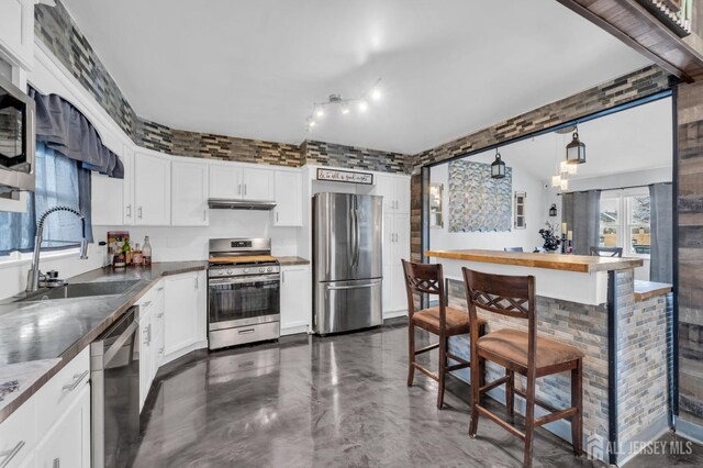 kitchen with sink, stainless steel appliances, decorative light fixtures, and white cabinetry