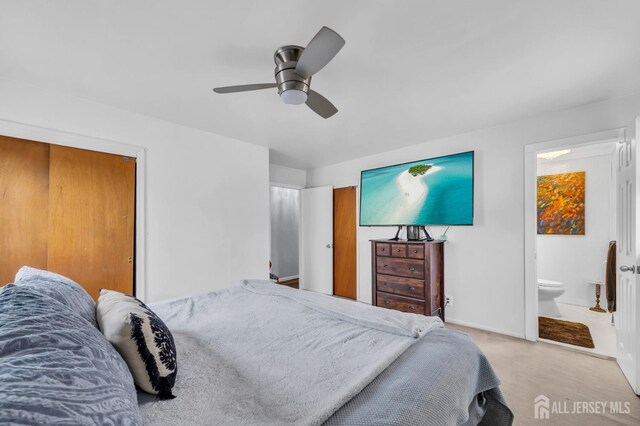 bedroom with connected bathroom, light carpet, a closet, and ceiling fan