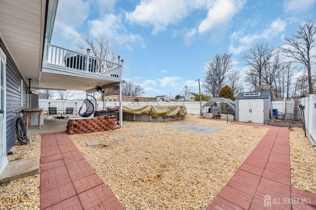 view of yard featuring a patio area, a covered pool, and a shed