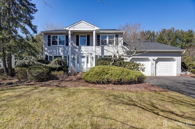 neoclassical home with a garage, a front yard, and driveway