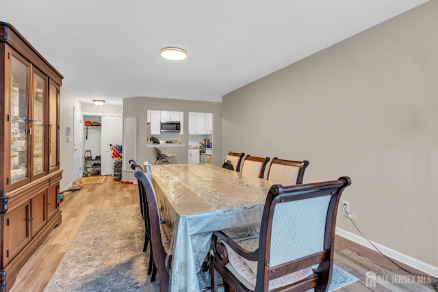 dining space with baseboards and light wood-style flooring