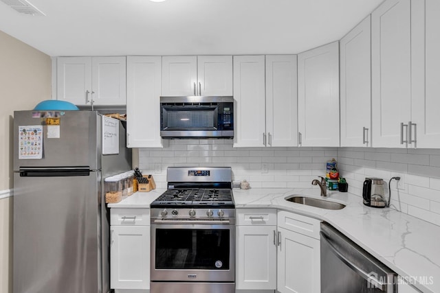 kitchen with appliances with stainless steel finishes, visible vents, white cabinets, and a sink