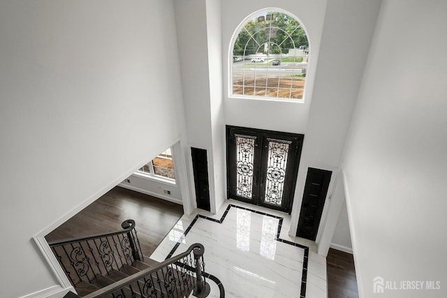 foyer featuring french doors, a towering ceiling, and wood-type flooring