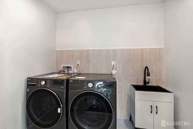 washroom with cabinets, washer and clothes dryer, and sink