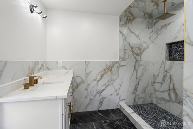 bathroom with a tile shower, vanity, and tile walls