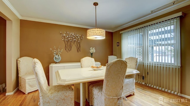 dining space featuring light wood-style floors, crown molding, and baseboards