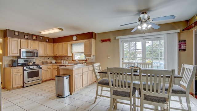 kitchen featuring appliances with stainless steel finishes, a sink, backsplash, light countertops, and a ceiling fan