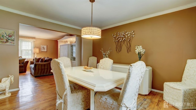 dining room featuring crown molding, wood finished floors, and baseboards