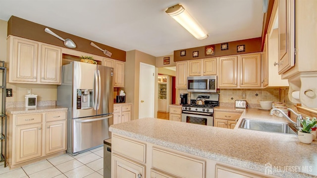 kitchen featuring stainless steel appliances, a sink, light countertops, a peninsula, and decorative backsplash