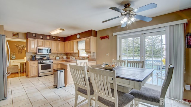 kitchen with stainless steel appliances, light tile patterned floors, light countertops, a ceiling fan, and light brown cabinetry