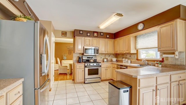 kitchen featuring appliances with stainless steel finishes, a sink, light countertops, light tile patterned floors, and backsplash