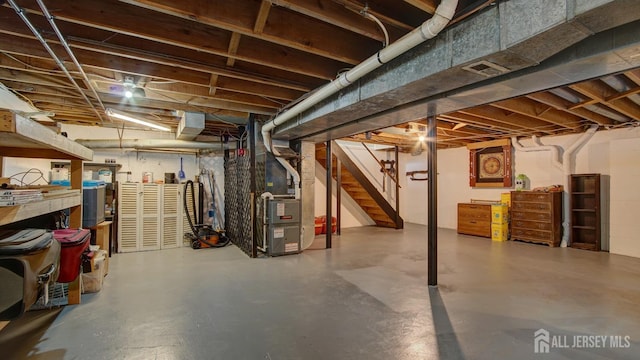 unfinished basement featuring heating unit and stairway