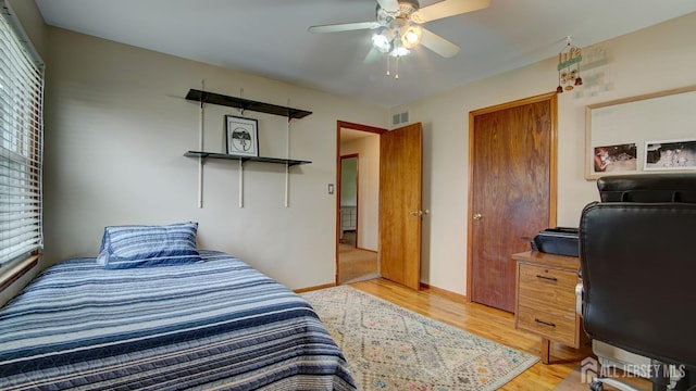 bedroom featuring light wood-style flooring, an office area, baseboards, and ceiling fan