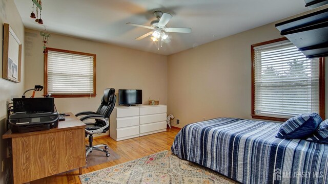 bedroom featuring light wood-style floors, an office area, and a ceiling fan