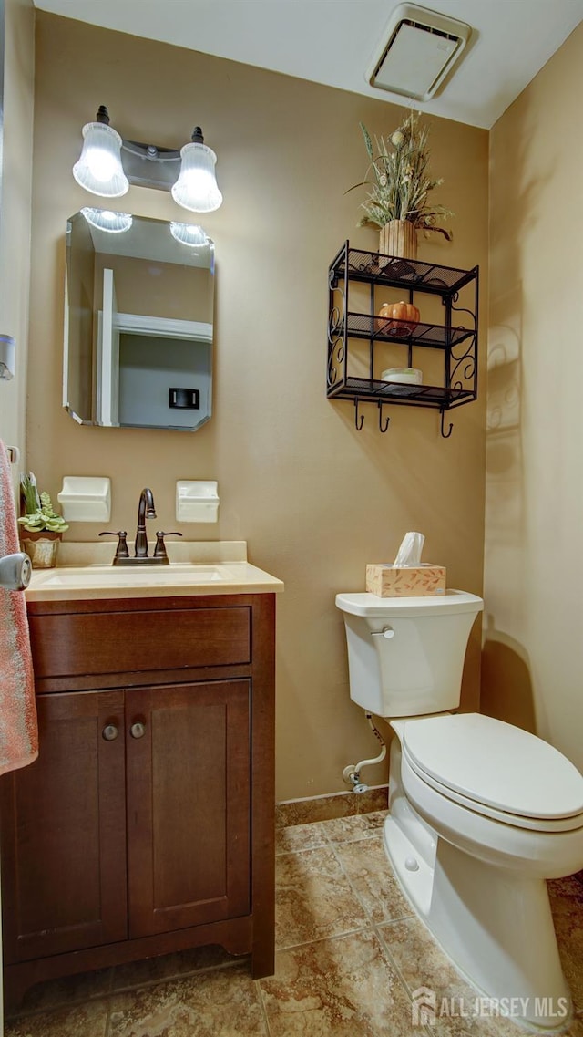 bathroom featuring toilet, vanity, and baseboards
