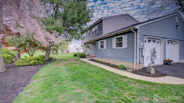 view of property exterior with an attached garage, a yard, and asphalt driveway
