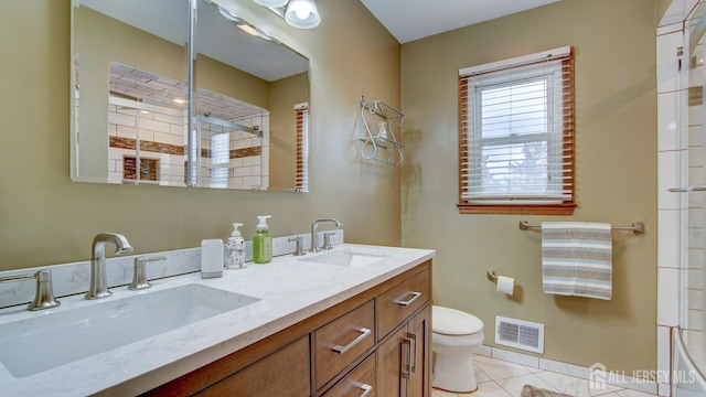 bathroom featuring toilet, a tile shower, tile patterned flooring, and double vanity