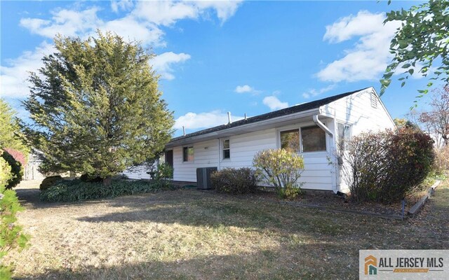 view of side of property featuring a yard and central AC