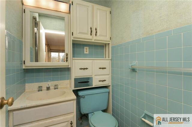 bathroom featuring vanity, tile walls, and toilet