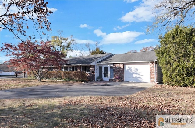 single story home featuring brick siding, driveway, and an attached garage