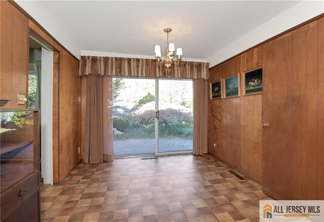 interior space featuring an inviting chandelier and wooden walls