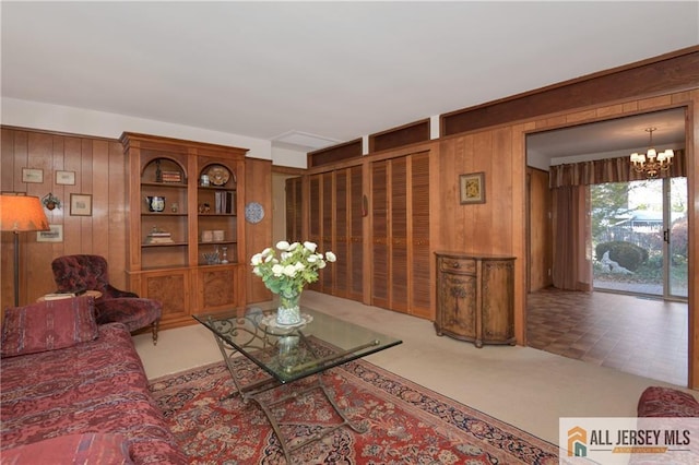 carpeted living room with a notable chandelier and wooden walls