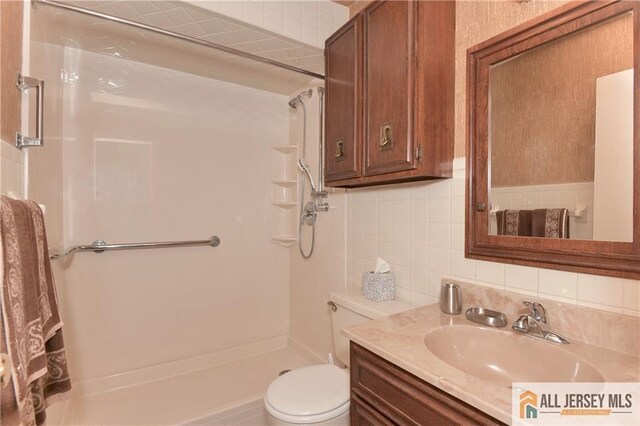 bathroom featuring vanity, backsplash, toilet, and walk in shower