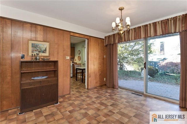 unfurnished dining area featuring a notable chandelier and wooden walls