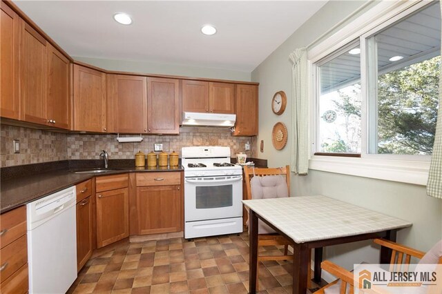 kitchen featuring sink, backsplash, and white appliances