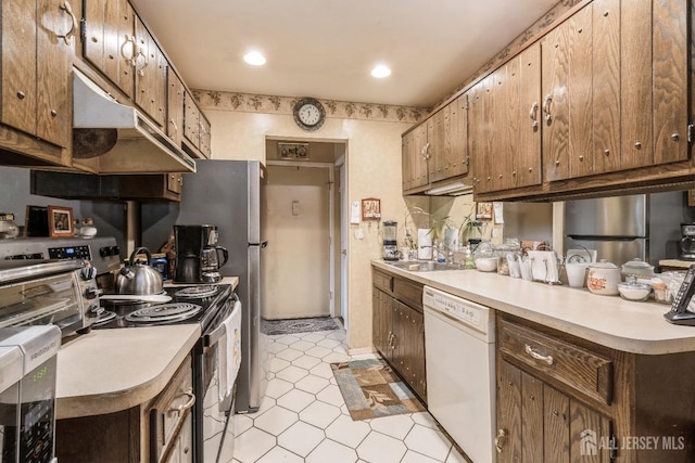 kitchen featuring light floors, stainless steel appliances, light countertops, a sink, and under cabinet range hood