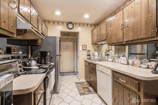 kitchen featuring a sink, under cabinet range hood, light tile patterned floors, light countertops, and appliances with stainless steel finishes