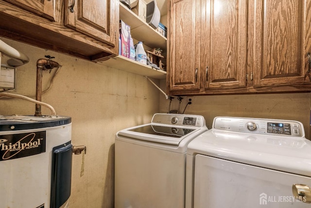 clothes washing area with cabinet space, electric water heater, and washer and dryer