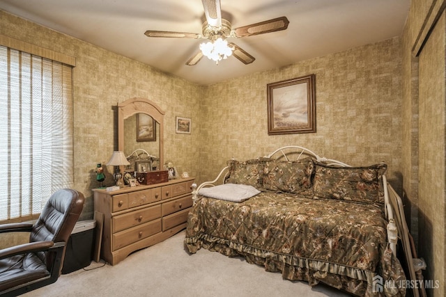 bedroom with wallpapered walls, a ceiling fan, and light colored carpet