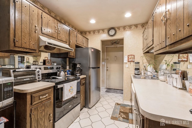 kitchen featuring a toaster, under cabinet range hood, a sink, light countertops, and appliances with stainless steel finishes