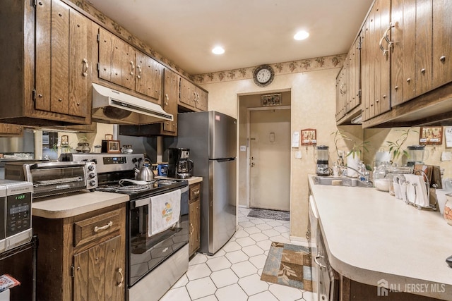 kitchen featuring a toaster, under cabinet range hood, appliances with stainless steel finishes, light countertops, and a sink