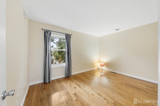 empty room featuring baseboards, visible vents, and light wood finished floors