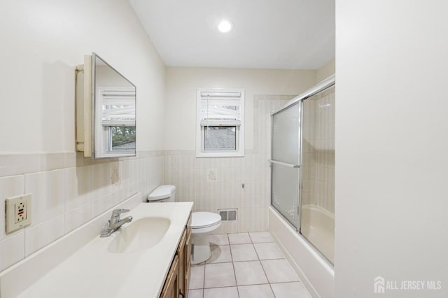 bathroom featuring toilet, tile walls, vanity, visible vents, and tile patterned floors