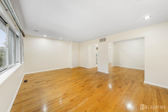 unfurnished room with light wood-type flooring, visible vents, and baseboards