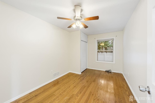 unfurnished room with light wood finished floors, baseboards, visible vents, and a ceiling fan