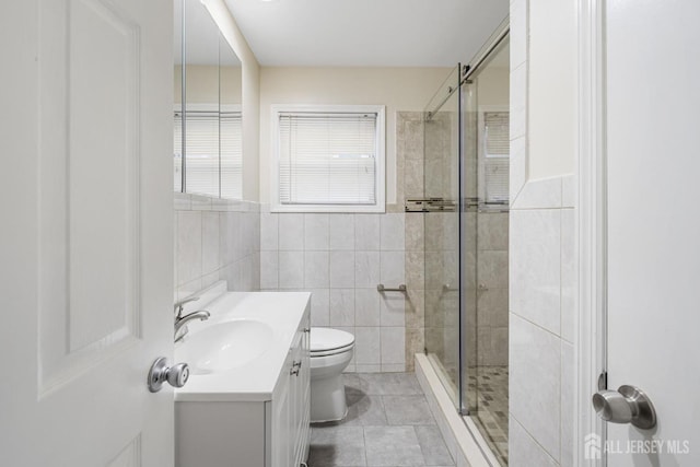 full bath with tile walls, toilet, a shower stall, vanity, and tile patterned floors