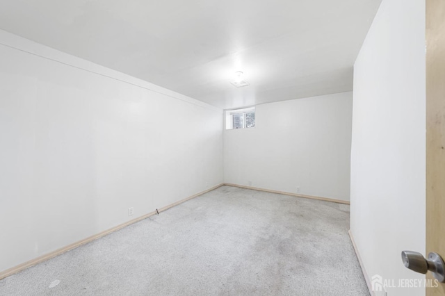 spare room featuring light carpet and baseboards