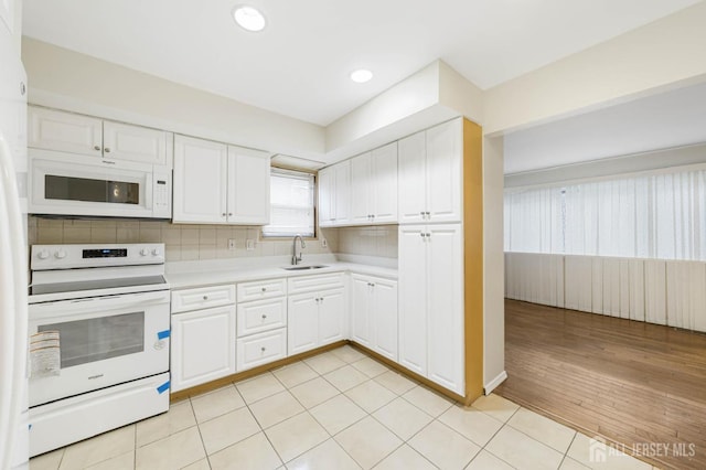 kitchen with white appliances, light countertops, a sink, and white cabinetry