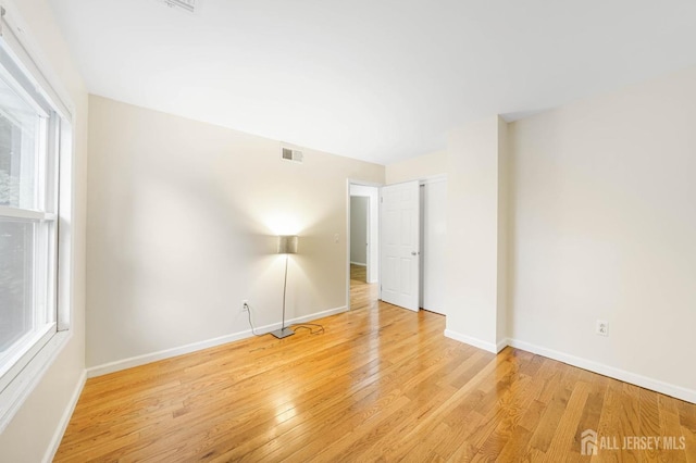 unfurnished bedroom with wood finished floors, visible vents, and baseboards