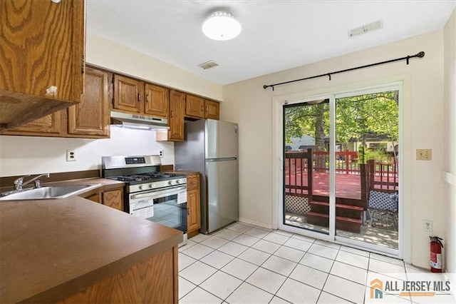 1383 Thomas Ave, North Brunswick, NJ 08902 - kitchen featuring stainless steel appliances, under cabinet range hood, brown cabinetry, dark countertops, and light tile patterned floors