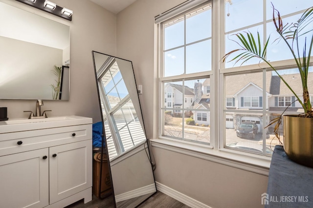 doorway to outside featuring dark wood-type flooring, baseboards, and a sink