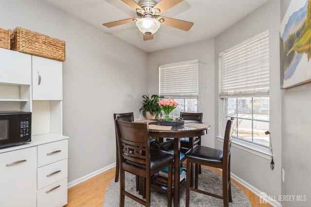 dining area with light wood finished floors, baseboards, and ceiling fan
