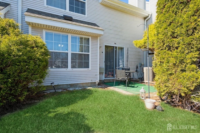 back of house with a chimney, a patio, central AC unit, and a lawn